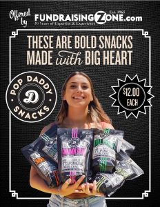 A cheerful woman stands in front of our vibrant promotional display, proudly holding a variety of Pop Daddy Snacks—available for just $12.00 each! With our enticing fundraising catalog selection and easy-to-sell products like Pop Daddy Snacks, raising money for your school or organization has never been more delicious—or more rewarding. Let us help you reach your goals with top-selling treats everyone will love!.