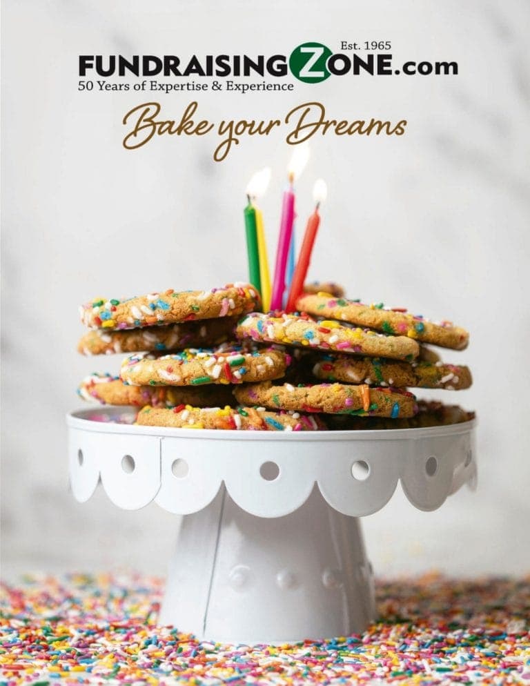 A stack of sprinkle cookies with candles sits on a cake stand, sprinkles all around. Text: "Bake your Dreams" FundraisingZone.com.
