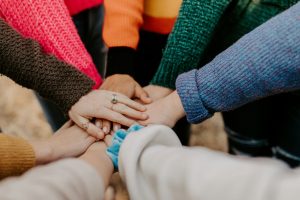 Team members gather in a circle, uniting their hands at the center—symbolizing partnership to achieve fundraising goals together.